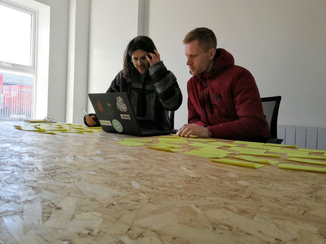 Seán and a colleague reviewing sticky notes at a laptop